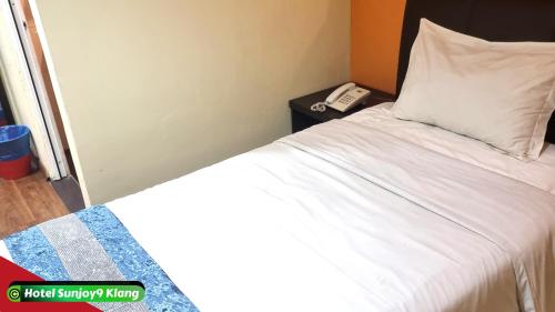 a bedroom with a bed with a phone on a night stand at Hotel Sunjoy9 Klang in Klang