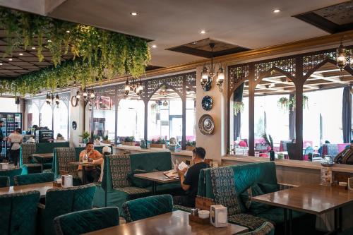 restauracja z zielonymi krzesłami i ludzie siedzący przy stołach w obiekcie Mardin Hotel w mieście Ałma-Ata