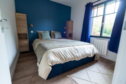 a blue bedroom with a bed and a window at Le Nichoir du Marais - écolodge in Ponts-et-Marais