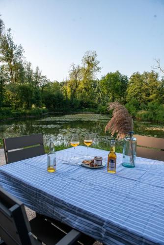 une table de pique-nique avec des verres à vin et une vue sur une rivière dans l'établissement Le Nichoir du Marais - écolodge, à Ponts-et-Marais