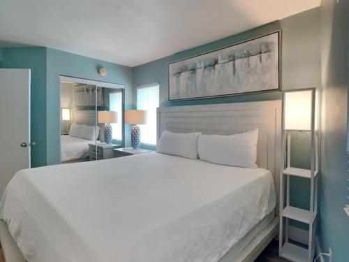- une chambre avec un grand lit blanc et un miroir dans l'établissement Lost Skye 46, à Perdido Key