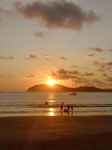a group of people walking on the beach at sunset at Casa Dulce Nombre in La Garita