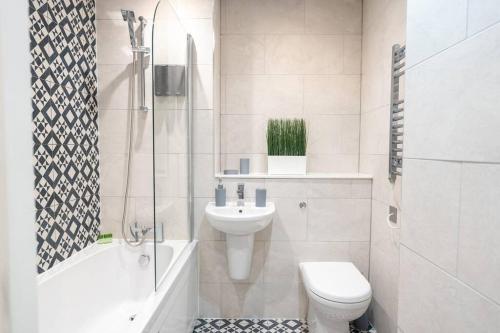 a white bathroom with a toilet and a sink at Century Central, Cardiff Bay, Modern Chic 2BR, Free Parking in Cardiff