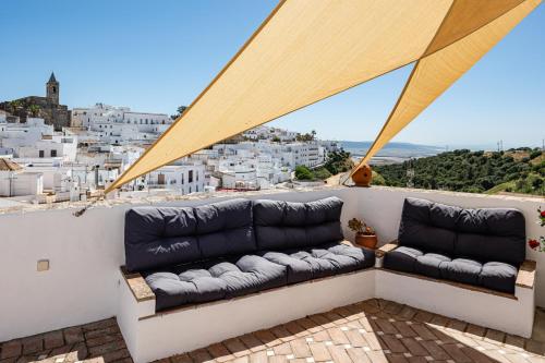 a couch on a balcony with a view of a city at Casa Lunarito in Vejer de la Frontera
