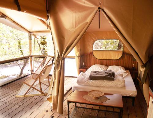 Camping L'Ondine de Provence في La Motte-Chalançon: غرفة نوم في خيمة مع سرير وطاولة