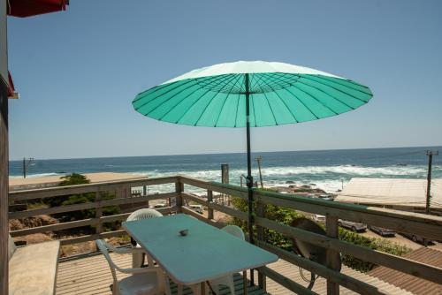 a table and an umbrella on a deck with the beach at Cabaña Ideal in Valparaíso