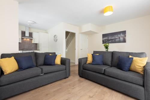 een woonkamer met twee grijze banken en gele kussens bij Oxheys House - 5 Bedrooms Contractors Parking in Preston