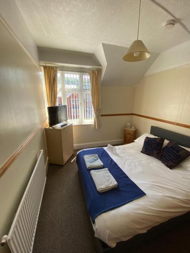 a small bedroom with a bed with a blue blanket at HQ Pencadlys in Prestatyn