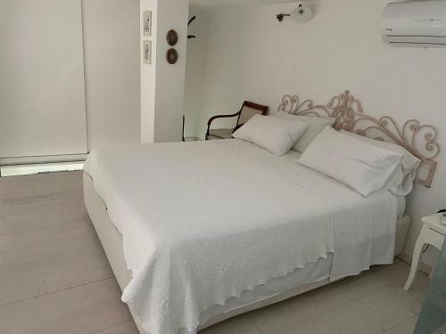 uma cama branca com lençóis e almofadas brancos em Dimora Sorrento em Sant'Agnello