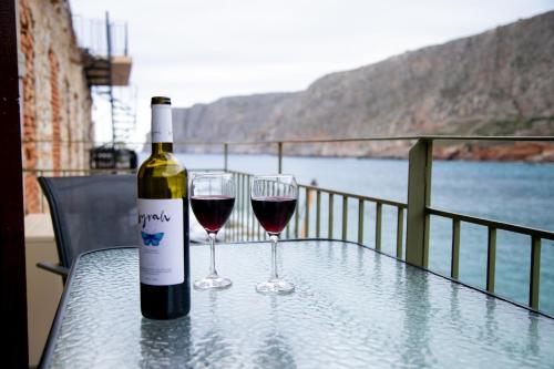 Una botella de vino y dos copas en una mesa. en Gerolimin Blue, en Yerolimin