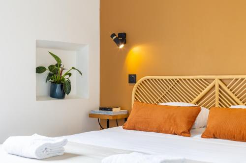 une chambre avec un lit avec des draps blancs et des oreillers orange dans l'établissement LIK APPARTS Thabor, à Rennes
