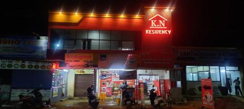 budynek skarbca Ken z ludźmi stojącymi na zewnątrz w nocy w obiekcie KN residency, near Trichy Airport w mieście Tiruchchirāppalli