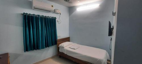 Habitación pequeña con cama y cortina verde en KN residency, near Trichy Airport, en Tiruchchirāppalli