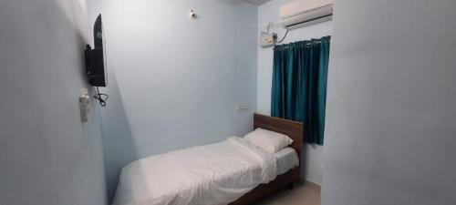 a small bedroom with a bed and a green curtain at KN residency, near Trichy Airport in Tiruchchirāppalli