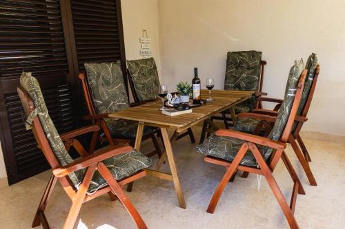 - une table et des chaises en bois avec des bouteilles de vin dans l'établissement Apartman Luma, à Krk