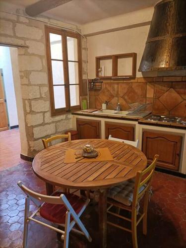 Il comprend une cuisine avec une table et des chaises en bois. dans l'établissement Appartement en hyper centre La clef des chants, à Avignon