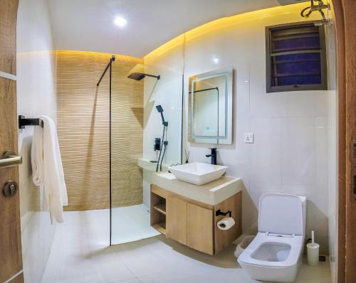 a bathroom with a toilet and a sink and a mirror at C. Apartments Annex in Abuja