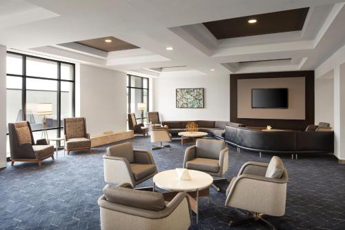 a lobby with couches and chairs and a television at Courtyard Louisville Airport in Louisville