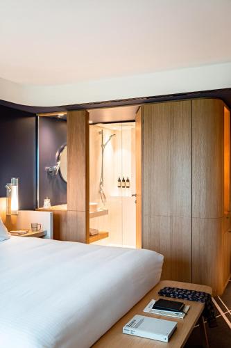 a bedroom with a bed and a shower and a table at Domaine de la Reine Margot Paris-Issy - MGallery Collection in Issy-les-Moulineaux