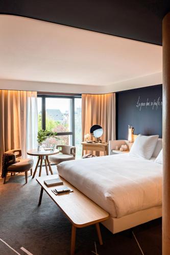 a bedroom with a large bed and a large window at Domaine de la Reine Margot Paris-Issy - MGallery Collection in Issy-les-Moulineaux
