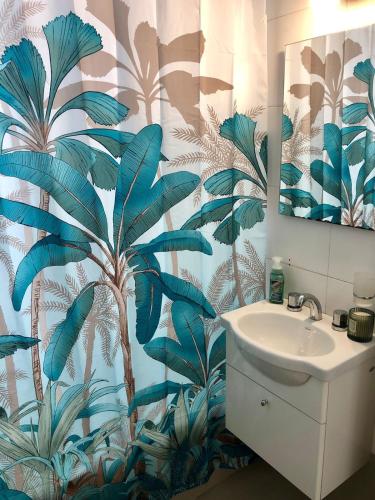 a bathroom with a sink and a palm tree shower curtain at Hermoso estudio amoblado con cochera MOVISTAR ARENA in Buenos Aires