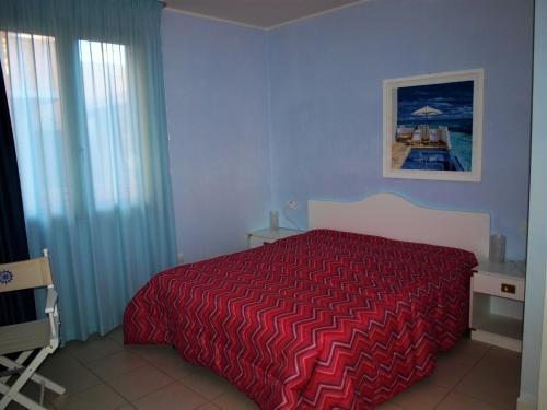 Schlafzimmer mit einem Bett mit einer roten Tagesdecke in der Unterkunft Pergola n.3 in Cavo
