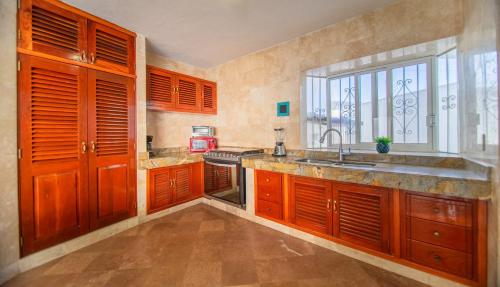 d'une cuisine avec des placards en bois, un évier et une fenêtre. dans l'établissement Casa Melanie, Alberca y Asador Privados, à Puerto Vallarta