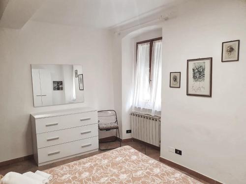 a white bedroom with a dresser and a mirror at Ubetty village center two-bedrooms apartment 5terreparco in Riomaggiore