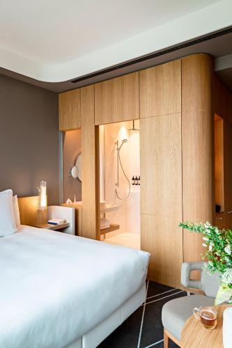 a bedroom with a large bed and a bathroom at Domaine de la Reine Margot Paris-Issy - MGallery Collection in Issy-les-Moulineaux