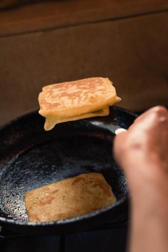 a person is flipping a piece of bread on a pan at Jnane Allia in Douar Soukkane