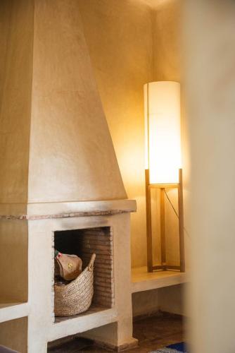 a living room with a fireplace with a lamp at Jnane Allia in Douar Soukkane