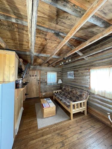 a room with a bed in a wooden cabin at Sportsman Lodge Melrose MT in Melrose