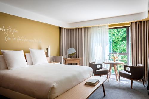 a bedroom with a large bed and a table and chairs at Domaine de la Reine Margot Paris-Issy - MGallery Collection in Issy-les-Moulineaux