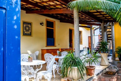 a patio with white tables and chairs and plants at Pousada Solar Azul in Lençóis