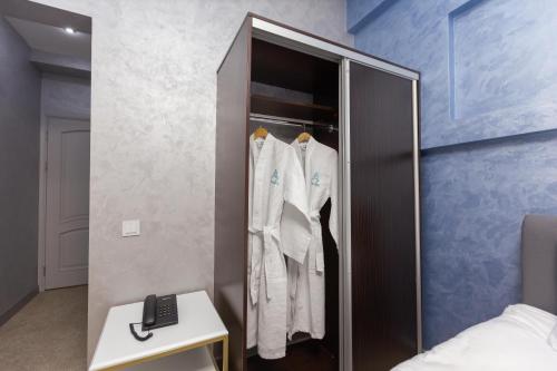 a wardrobe with white clothes in a bedroom at Amelia Hotel in Almaty