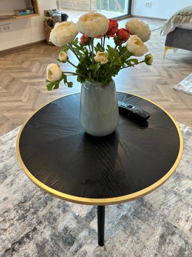 a round table with a vase with flowers on it at Transalpina Tiny House - outdoor jacuzzi in Baia de Fier