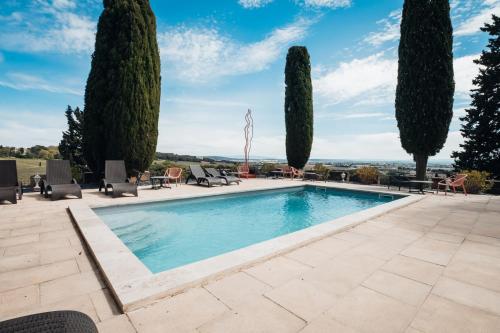 - une piscine bordée de chaises et d'arbres dans l'établissement Hostellerie du Château des Fines Roches, à Châteauneuf-du-Pape