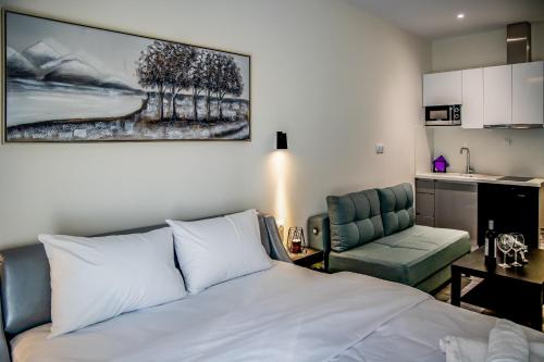 a bedroom with a bed and a chair and a kitchen at Diamond Suites 32 in Thessaloniki