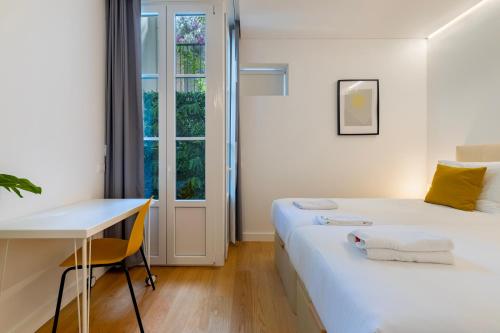 1 Schlafzimmer mit 2 Betten, einem Schreibtisch und einem Fenster in der Unterkunft Your Perfect Pantheon Stay in Lissabon