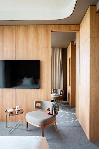 a living room with a couch and a tv on a wall at Domaine de la Reine Margot Paris-Issy - MGallery Collection in Issy-les-Moulineaux