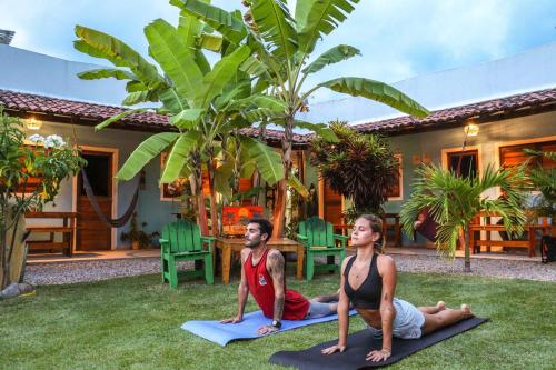 two people doing yoga in the yard of a house at Back to the Beach Hostel - Pipa in Pipa