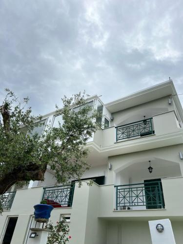 a white house with a blue chair in front of it at St Nicholas Tsilivi Apts in Planos