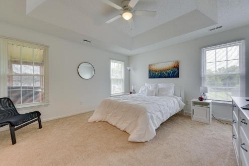 a white bedroom with a bed and a ceiling fan at Charlotte Vacation Rental Near Motor Speedway! in Charlotte
