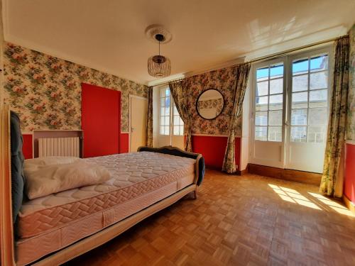 ein Schlafzimmer mit einem Bett und einer roten Wand in der Unterkunft Maison de caractère / Petit Versailles Normand in Valognes