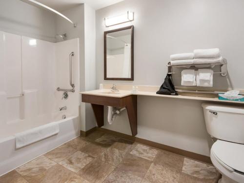 a bathroom with a toilet and a sink and a tub at Midtown Suites - Greenville in Greenville