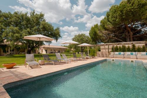 uma piscina com espreguiçadeiras e guarda-sóis ao lado em Casa das Cegonhas em Vale de guiso