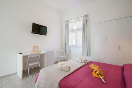 a bedroom with a bed with pink sheets and a desk at CalaBisso in Calasetta