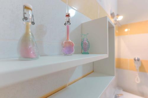 three glass bottles sitting on a shelf in a bathroom at CalaBisso in Calasetta