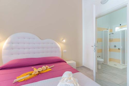 a bedroom with a white bed with a large white headboard at CalaBisso in Calasetta