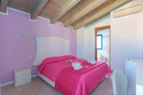 a bedroom with a pink bed with a pink blanket at CalaBisso in Calasetta